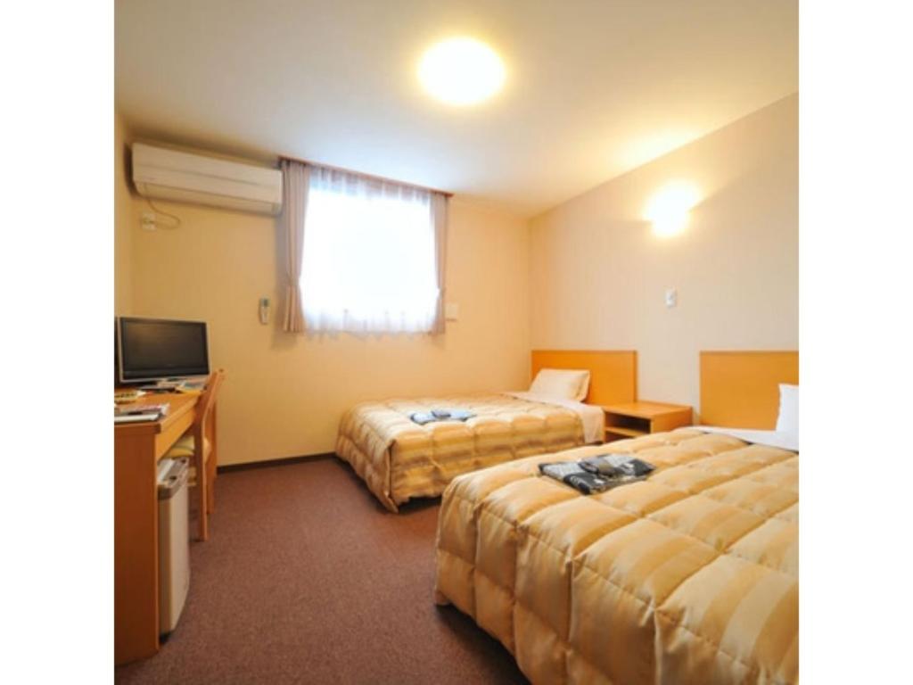 Tennen Onsen Kakenagashi no Yado Hotel Pony Onsen - Vacation STAY 50916v في تووادا: غرفة فندقية بسريرين ومكتب
