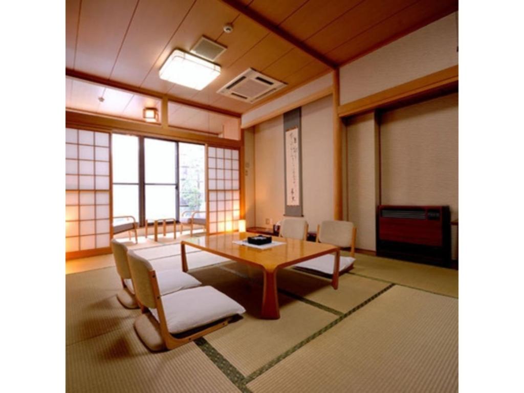 una grande stanza con tavolo, sedie e finestre di Tennen Onsen Kakenagashi no Yado Hotel Pony Onsen - Vacation STAY 50872v a Towada