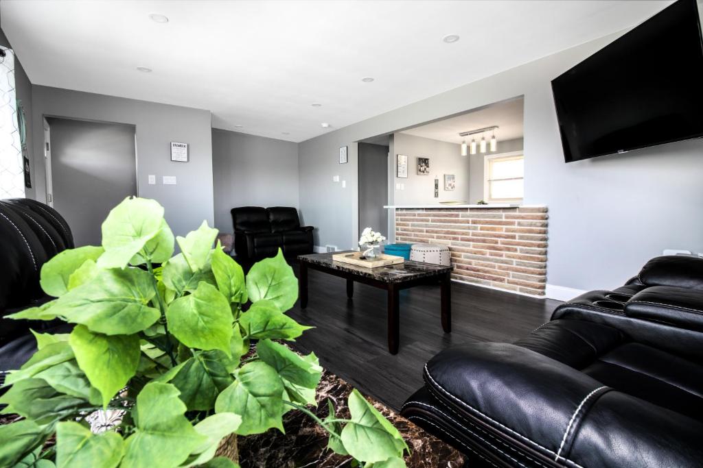a living room with black leather furniture and a large plant at The Grand Gorge Villa-With Private Yard & Parking, Minutes From Falls & Casino by Niagara Hospitaliy in Niagara Falls