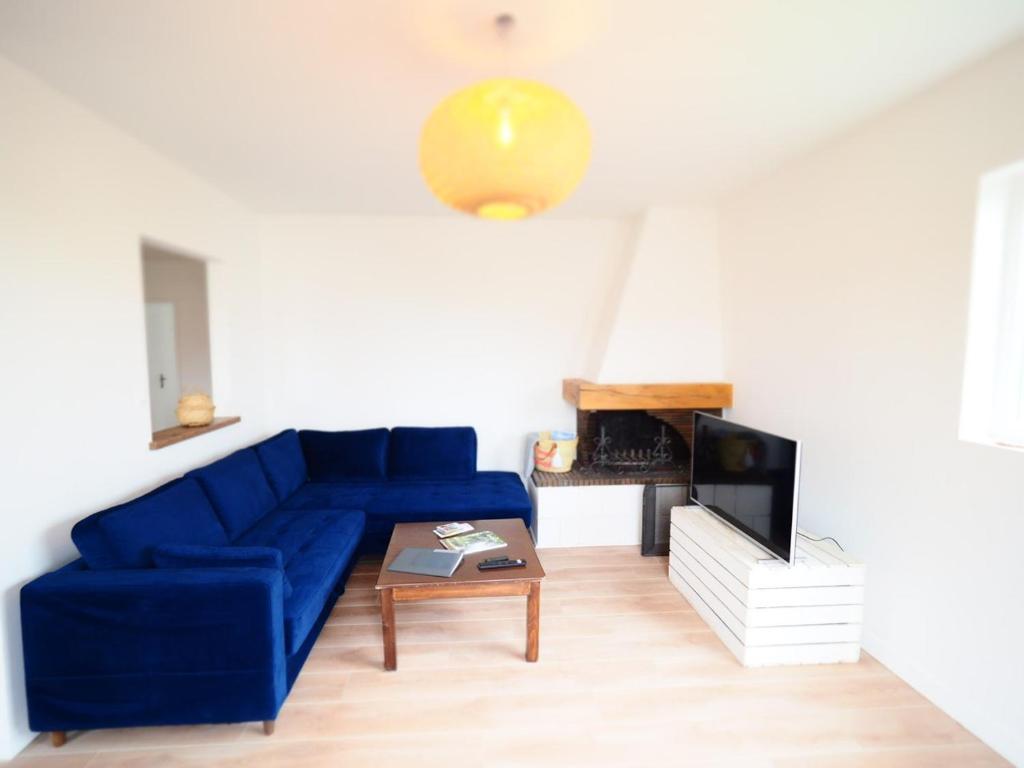 sala de estar con sofá azul y TV en NOUVEAUTE 2023 Maison Cocooning avec jardin, Terrasse couverte et Jacuzzi en Bellerive-sur-Allier