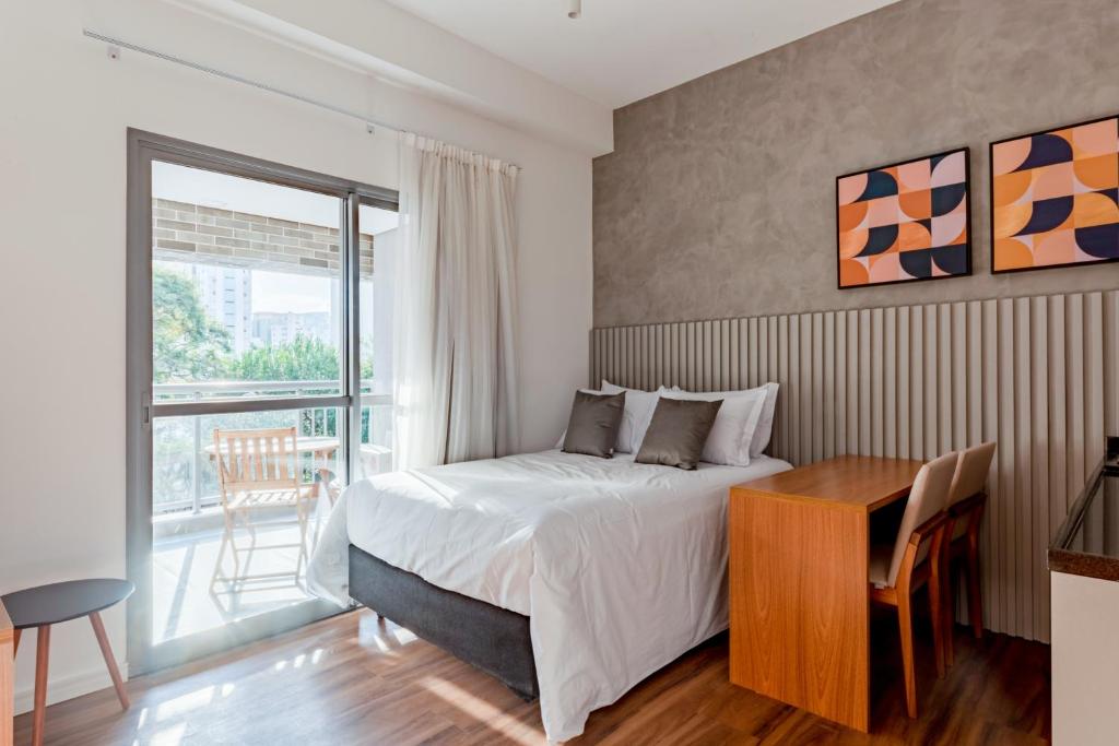 um quarto com uma cama, uma secretária e uma janela em Tabas - Edifício Z. Pinheiros em São Paulo