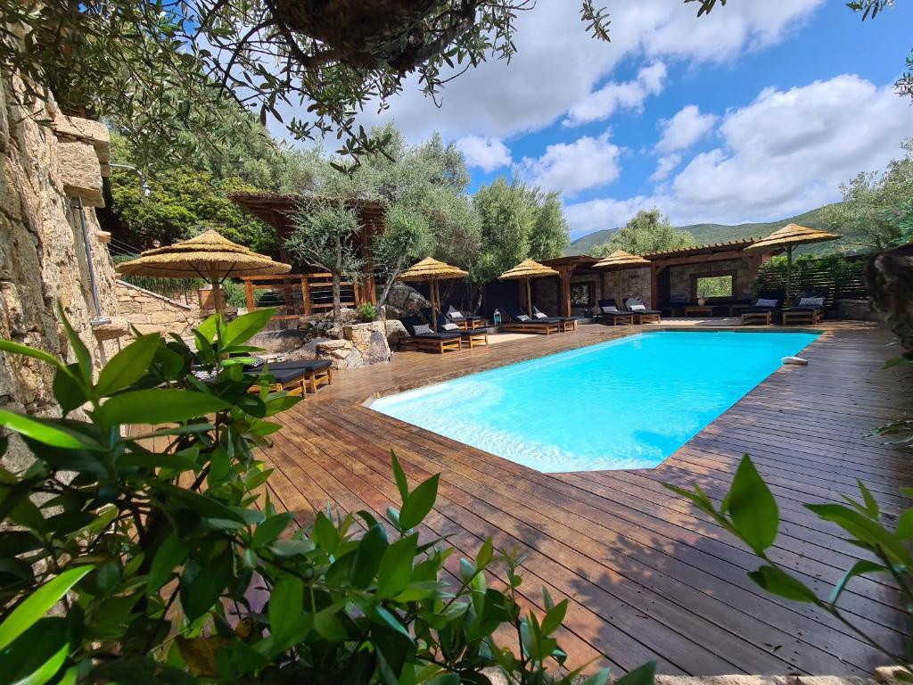 einen Pool mit Stühlen und Sonnenschirmen auf einer Holzterrasse in der Unterkunft Chambre d'hôte Casa Maredda in Porticcio