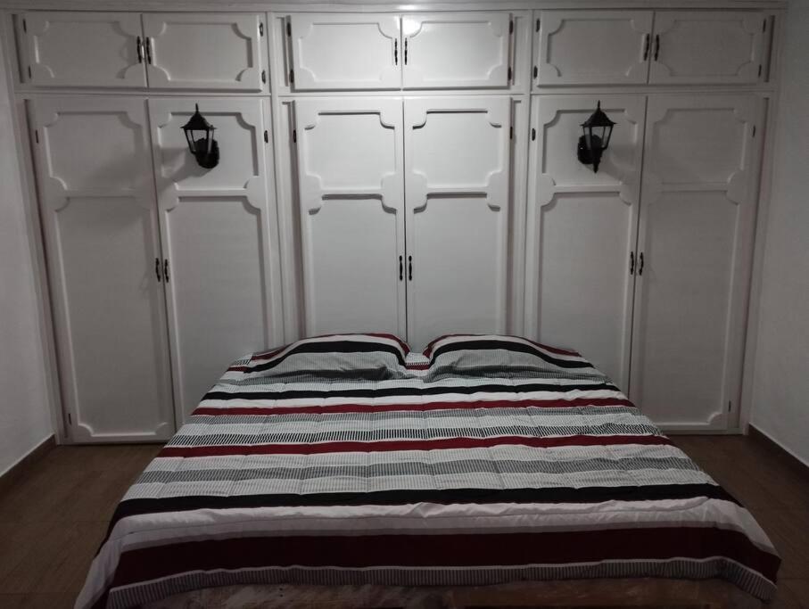 1 dormitorio con armarios blancos y 1 cama con manta a rayas en Depto. con Jacuzzi aeropuerto, en Chihuahua