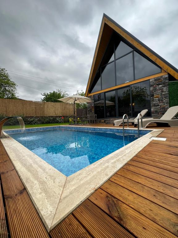 a swimming pool on a wooden deck with a house at ROSE SAPANCA STONE HOUSE in Sakarya