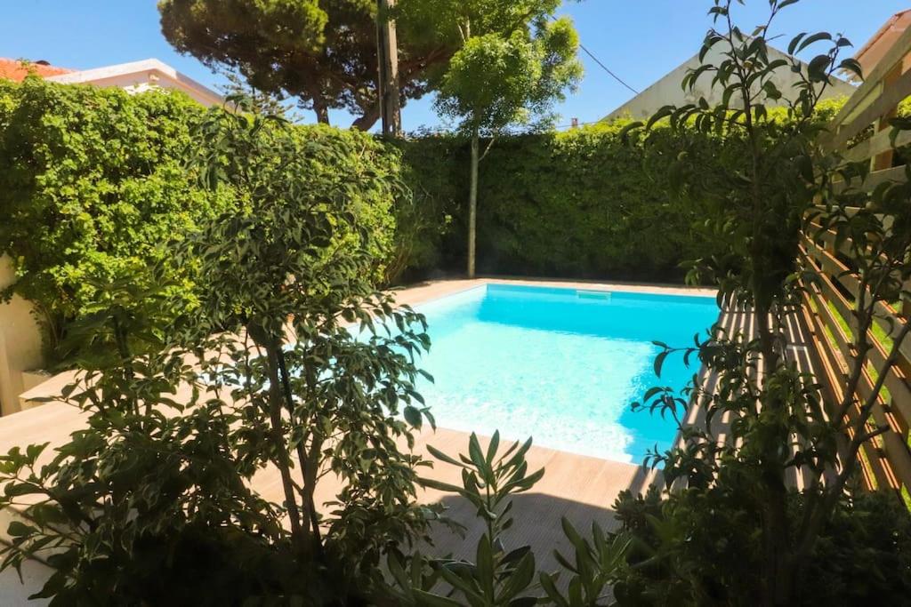 a swimming pool in a yard with bushes at Cascais Getaway with a shared pool in Cascais