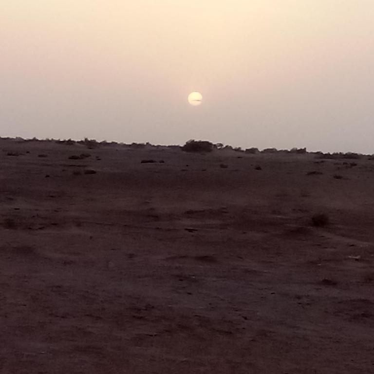 a sunset in the desert with the sun in the sky at dar Brahim in Mhamid