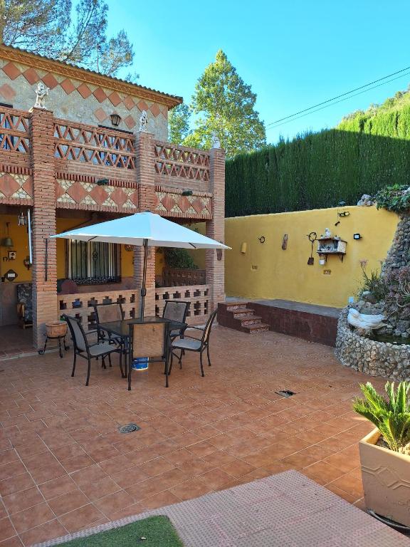 un patio con mesa, sillas y sombrilla en VILLA EL SALADO -ALQUILER RURAL ISABEL en Arriate