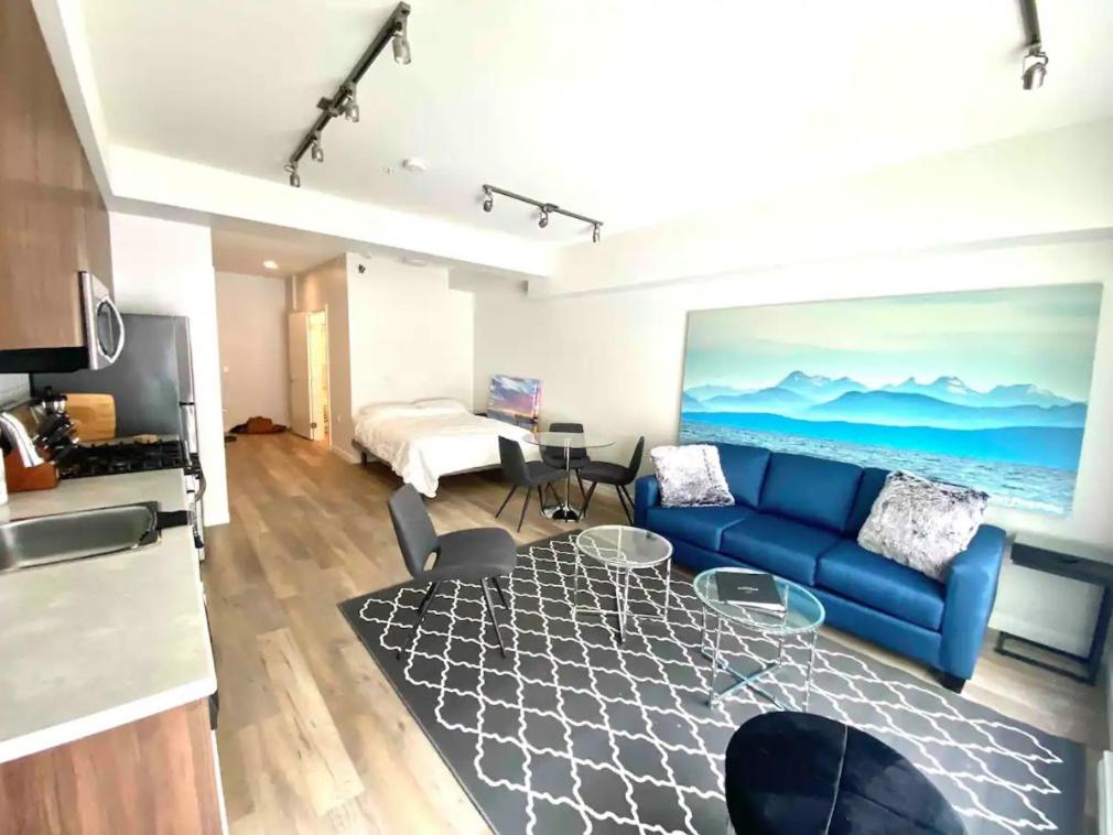 ein Wohnzimmer mit einem blauen Sofa und einem Tisch in der Unterkunft Perfect Brand New Studio Downtown Sidney in Sidney