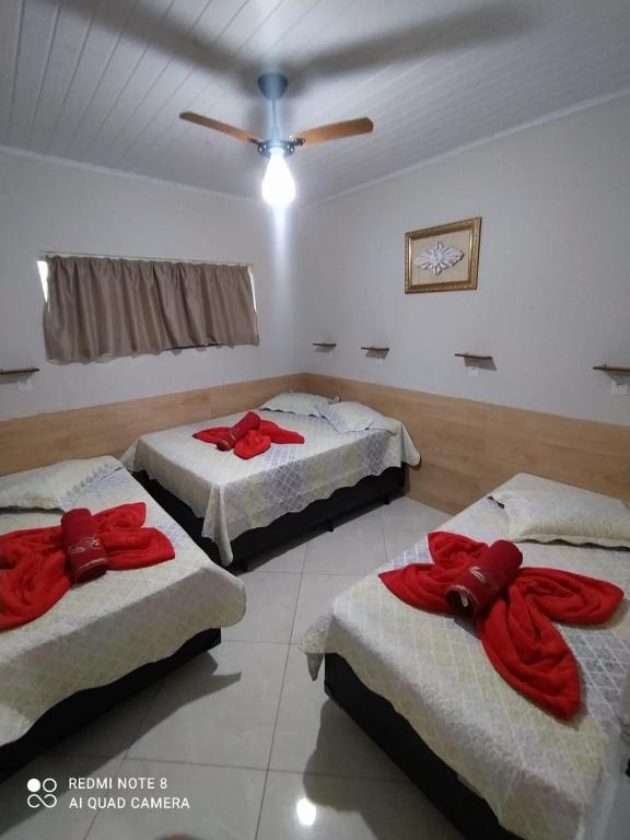 a room with three beds with red bows on them at Casa Completa com Garagem a 400mts da basilica in Aparecida