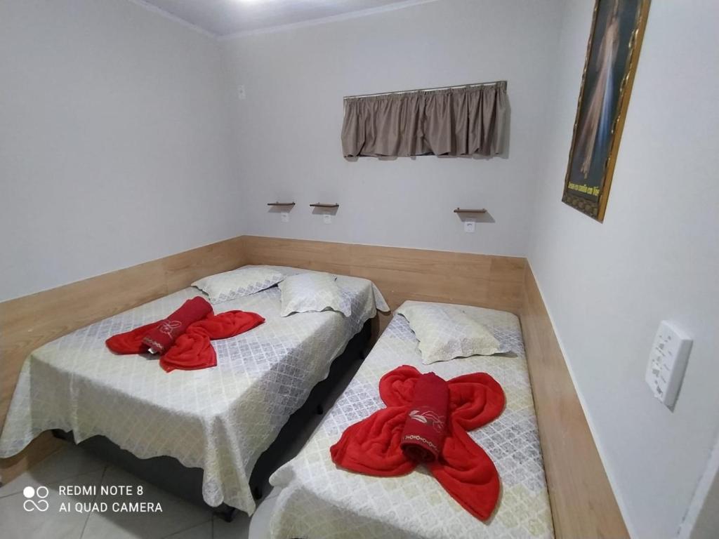 two beds in a room with red towels on them at Casa Completa com Garagem a 400mts da basilica in Aparecida
