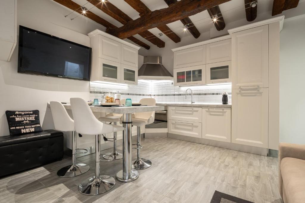 - une cuisine avec des placards blancs, une table et des chaises dans l'établissement Rialto Boutique Apartment, à Venise