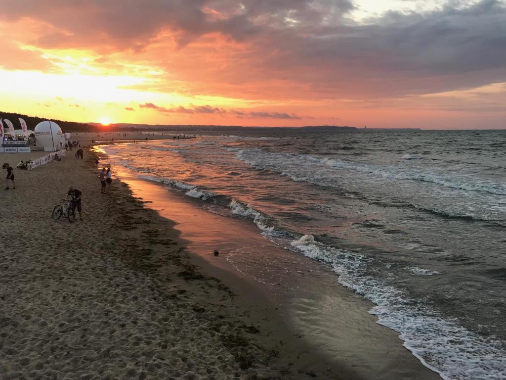 een strand bij zonsondergang met mensen die op het zand lopen bij Sopot Sea Apartments in Sopot