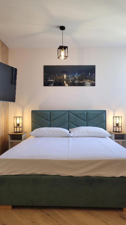 a bedroom with a large bed with white sheets and lights at Apartament Sienkiewicza 22 in Zamość