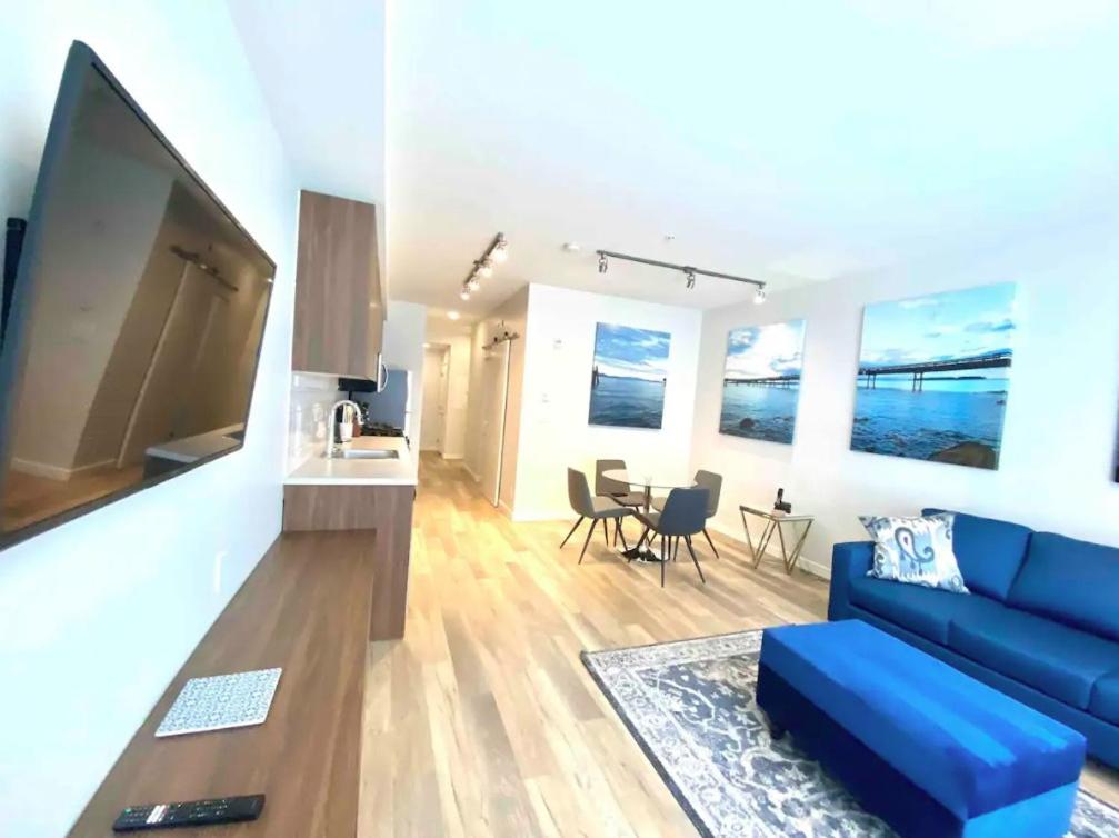 een woonkamer met een blauwe bank en een tv bij Perfect Brand New Condo In The Heart of Sidney in Sidney