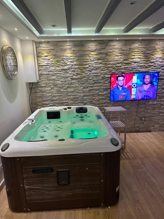 bañera de hidromasaje en una habitación con TV en Agréable Maison avec jacuzzi en Maisdon-sur-Sèvre