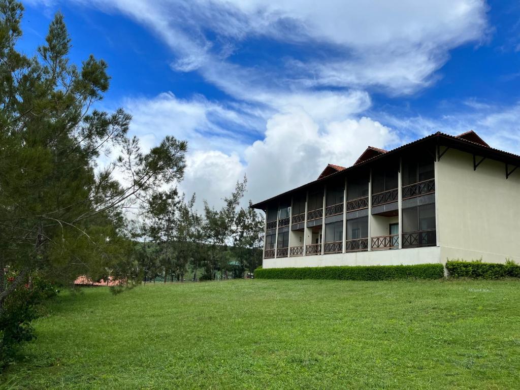 un edificio con un campo verde delante de él en Monte Castelo Flat 08B, en Gravatá