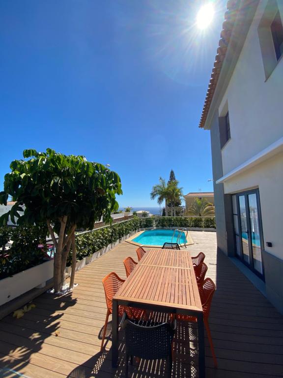 drewniany stół i krzesła przy basenie w obiekcie Sunset of Duke#Luxury Costa Adeje w Adeje