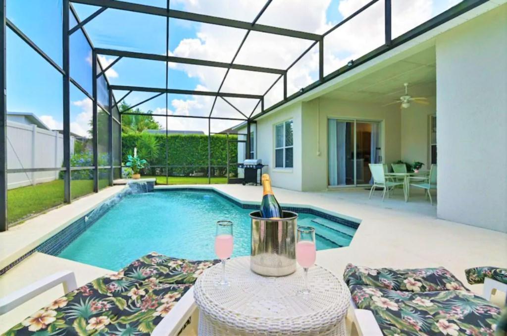una casa con piscina e una bottiglia di vino sul tavolo di RL236BD Universal Kingdom 8 guests pool home a Davenport