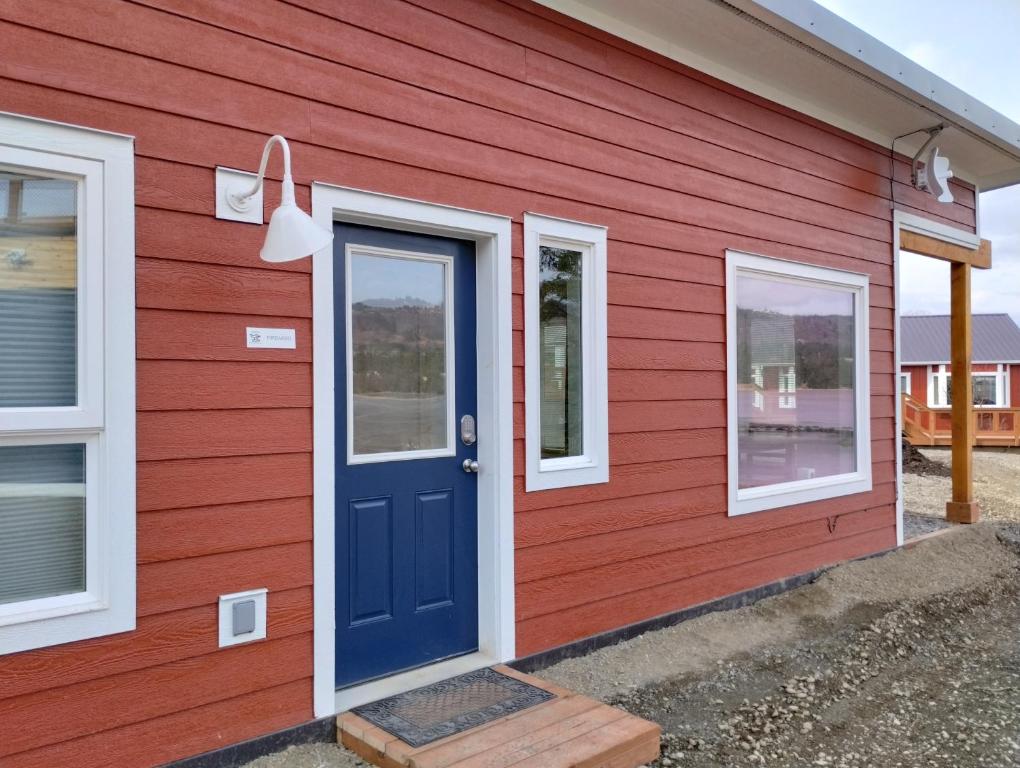 ein rotes Haus mit einer blauen Tür und Fenstern in der Unterkunft Fireweed Cabin - Homer Seaplane Base in Homer