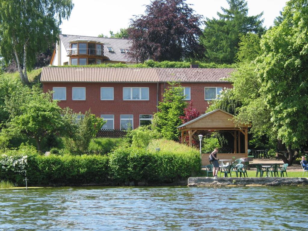 Eine Frau steht vor einem Gebäude neben einem Fluss. in der Unterkunft Gasthof am See in Seedorf