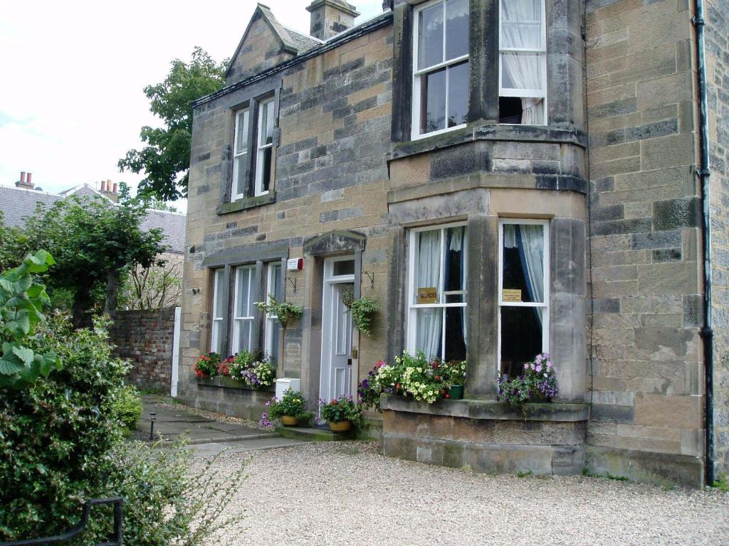 una vieja casa de ladrillo con flores delante en Aynetree Guest House, en Edimburgo