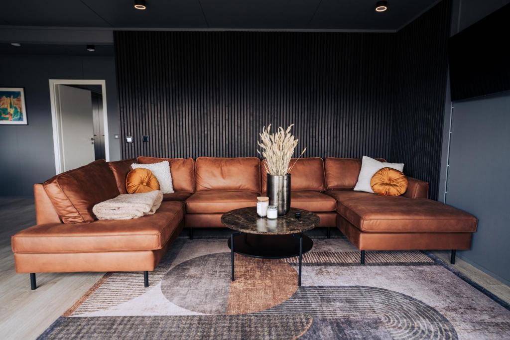 a brown leather couch in a living room with a table at Golden Circle Luxury Cottages in Selfoss