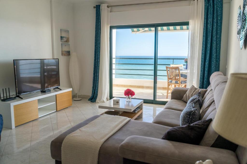 a living room with a couch and a tv and the ocean at Ocean Blue II in Quarteira