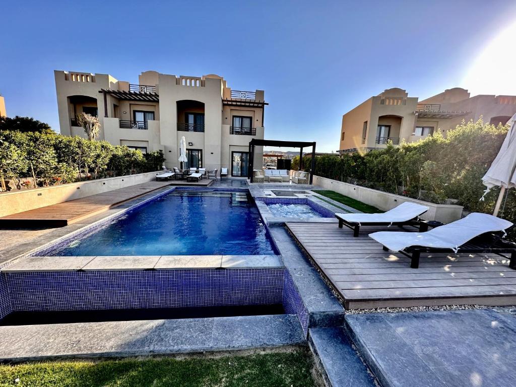 a house with a swimming pool in front of a building at Luxurious Villa with Infinity Private Pool & Jacuzzi over Sabina Island's Lagoon in Hurghada