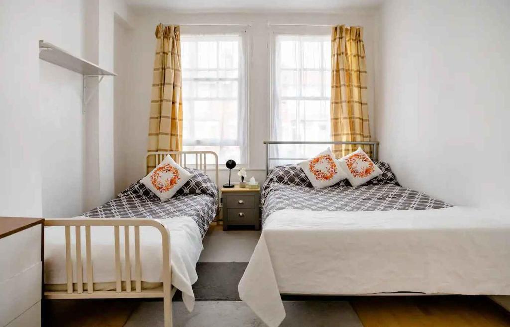 two beds in a bedroom with two windows at Homestay near Tottenham Hotspur Stadium in London