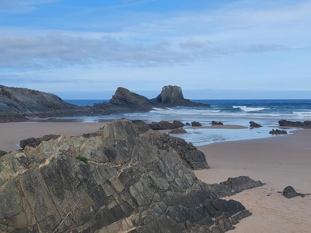 una playa con algunas rocas y el océano en a casinha da avó, en Zambujeira do Mar