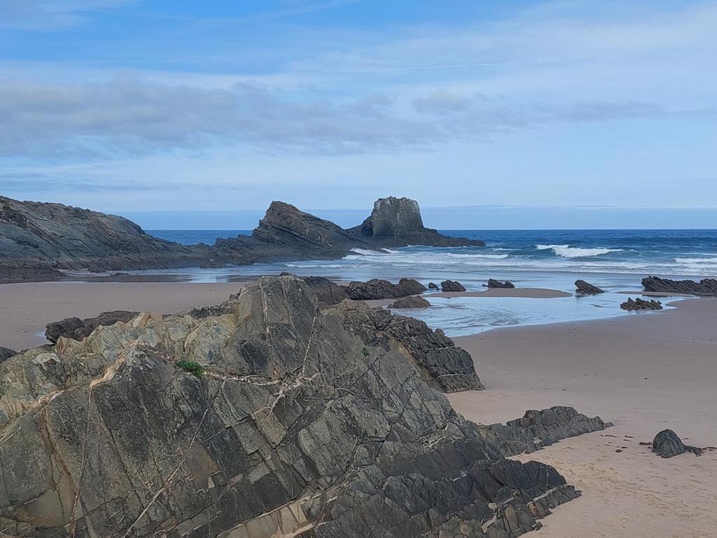 a beach with some rocks and the ocean at a casinha da avó in Zambujeira do Mar