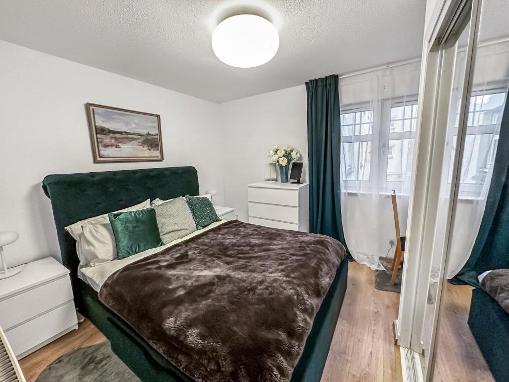Schlafzimmer mit einem Bett mit einem grünen Kopfteil in der Unterkunft Comfortable 2 Bedroom Flat In The City Centre in Edinburgh