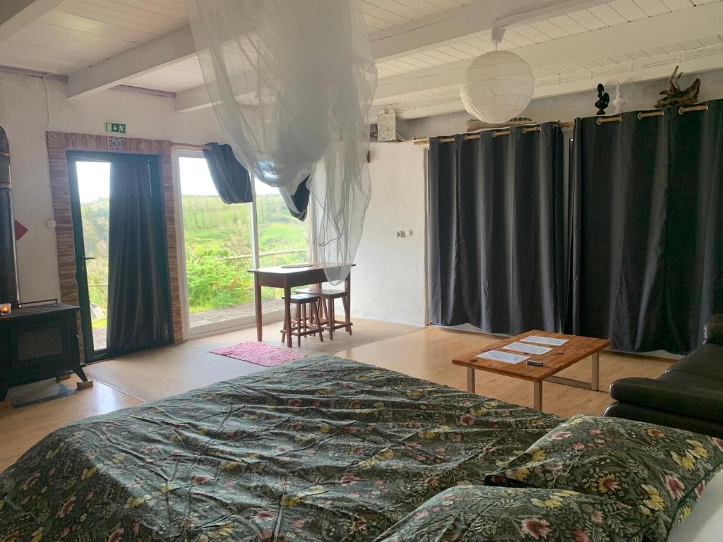 ein Schlafzimmer mit einem Bett, einem Tisch und einem Stuhl in der Unterkunft House with Forest View in Lajes das Flores