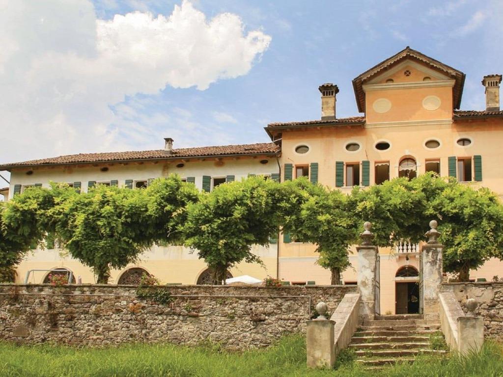 una grande casa con un muro in pietra e scale di Charming apartment in Santa Giustina with shared swimming pool a Santa Giustina