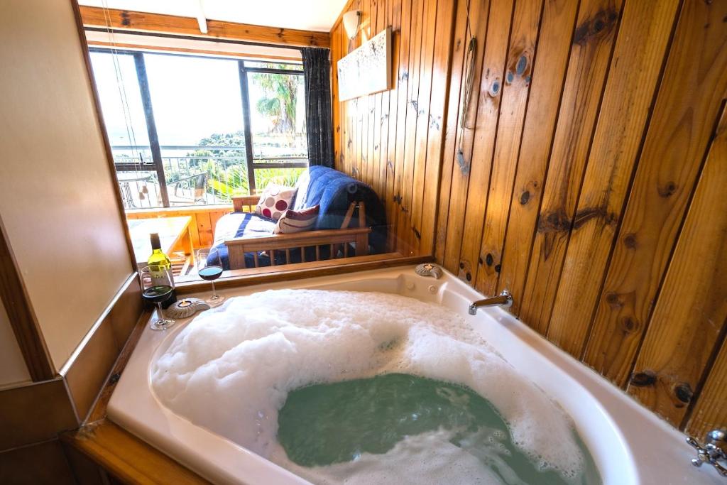 a large bath tub in a room with a window at Palm Beach - SupaCute Cottage, Sky TV, Wifi and possibly a Car in Palm Beach