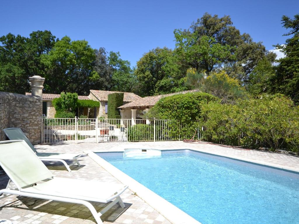 a swimming pool with two lawn chairs next to a house at Holiday home with garden and private pool in Vaison-la-Romaine