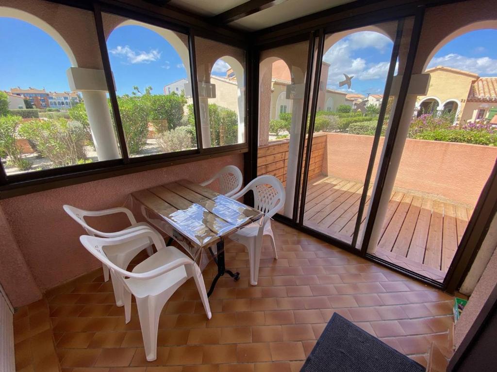 a porch with a table and chairs and windows at Villa Port Barcarès, 2 pièces, 4 personnes - FR-1-81-259 in Le Barcarès