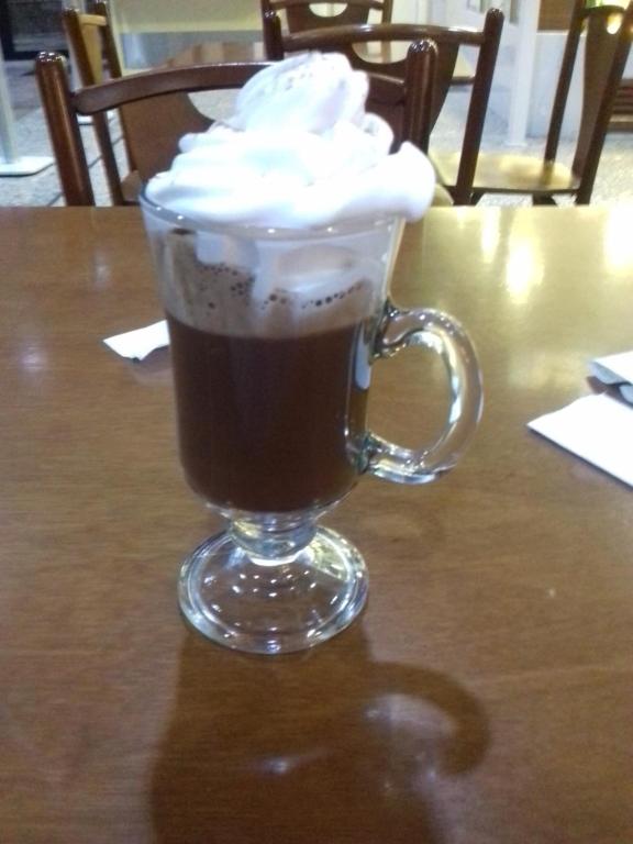 a glass cup of coffee with whipped cream on a table at Man's Place Hostel Masculino in Porto Alegre