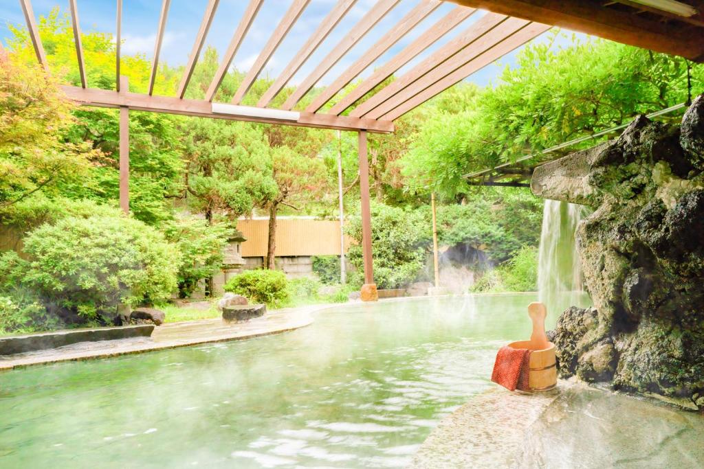 a swimming pool with a waterfall in a backyard at Ooedo Onsen Monogatari Kakeyu in Ueda