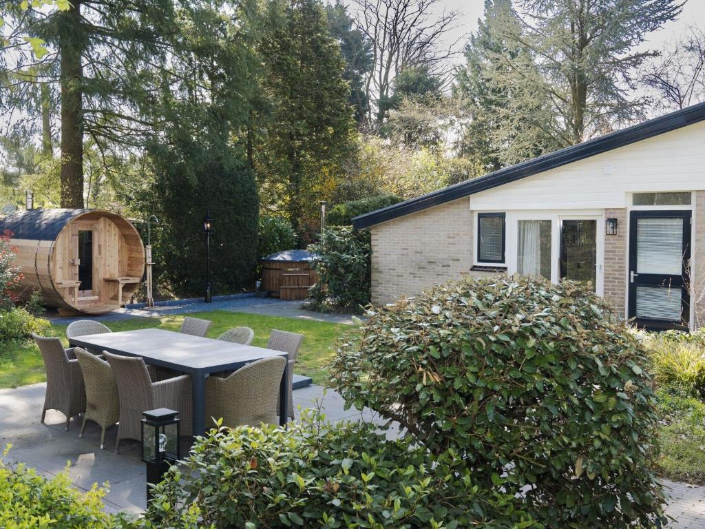 a patio with a table and chairs in a yard at Attractive bungalow with sauna and hot tub in Voorthuizen