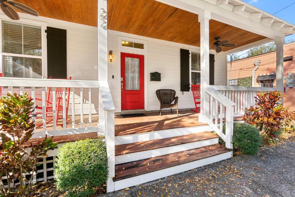 a white house with a red door and stairs at Fullerwood Delight- Mins to Beach and Downtown in St. Augustine