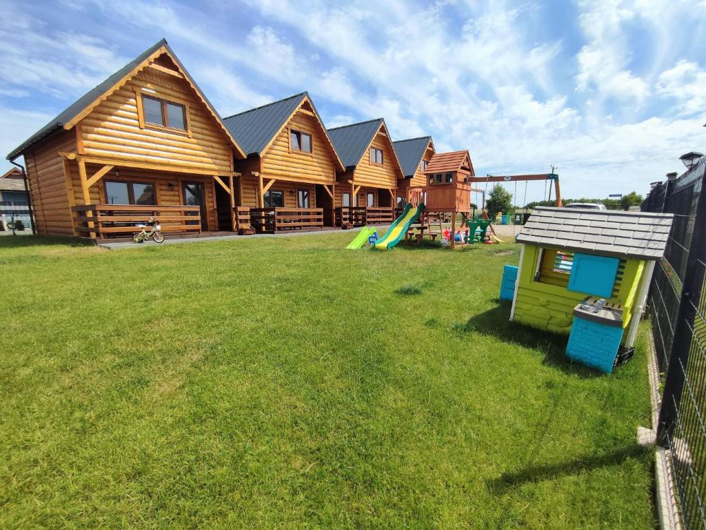 a log house with a playground in the yard at Family Resort in Niechorze near Lighthouse in Niechorze