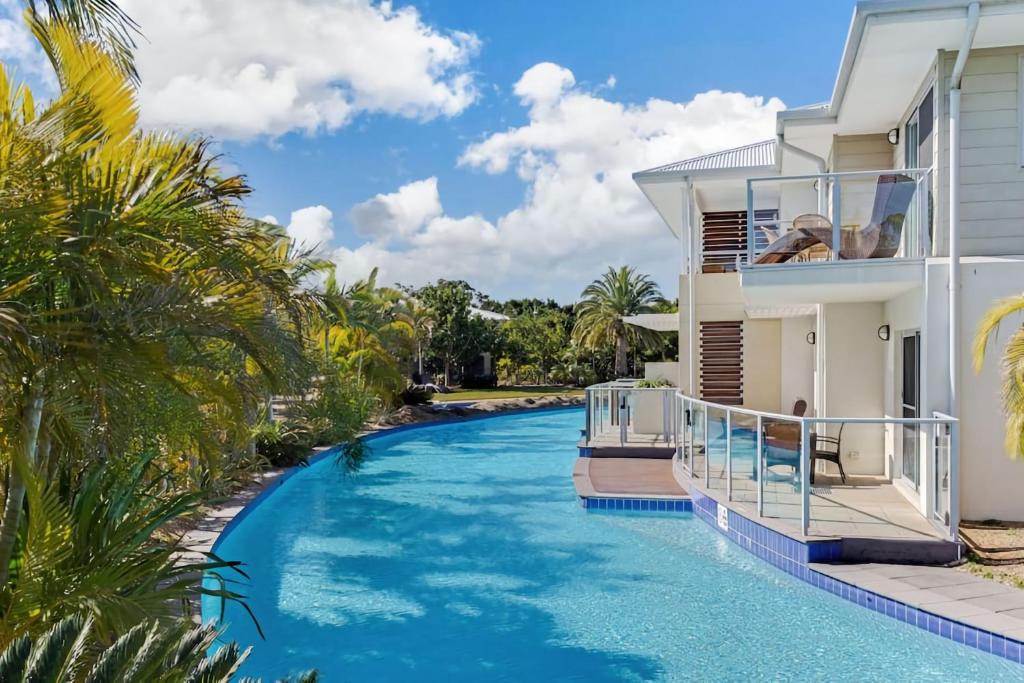 a swimming pool in front of a house with palm trees at Oaks Pacific Blue Pool spa more in complex in Salamander Bay