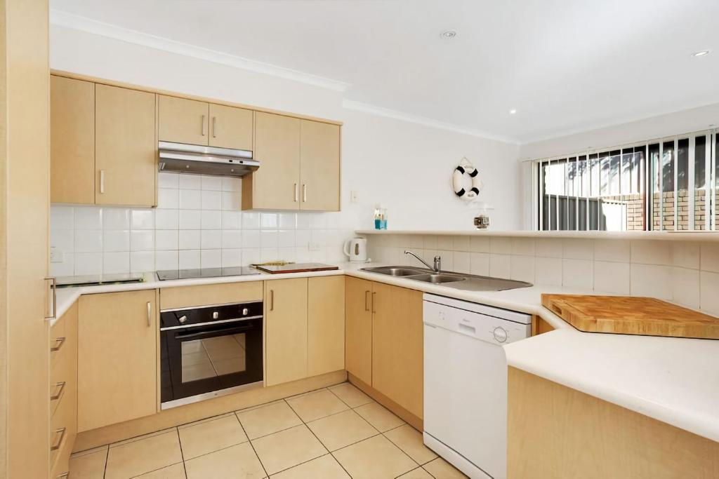 a kitchen with wooden cabinets and white appliances at Townhouse in the heart of Port Stephens in Salamander Bay