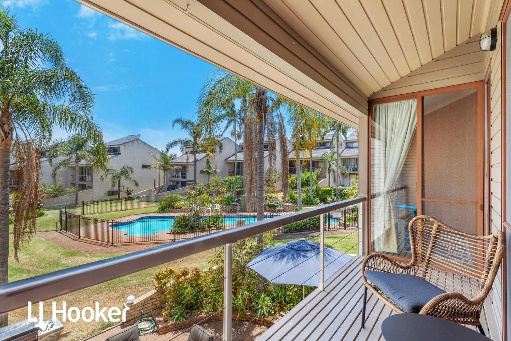 a balcony with a view of a pool and palm trees at Amazing waterfront location in Soldiers Point