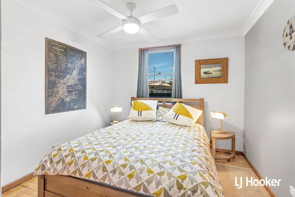 a bedroom with a bed with yellow pillows and a window at Cromarty Beach Cottage in the Heart of Anna Bay in Anna Bay