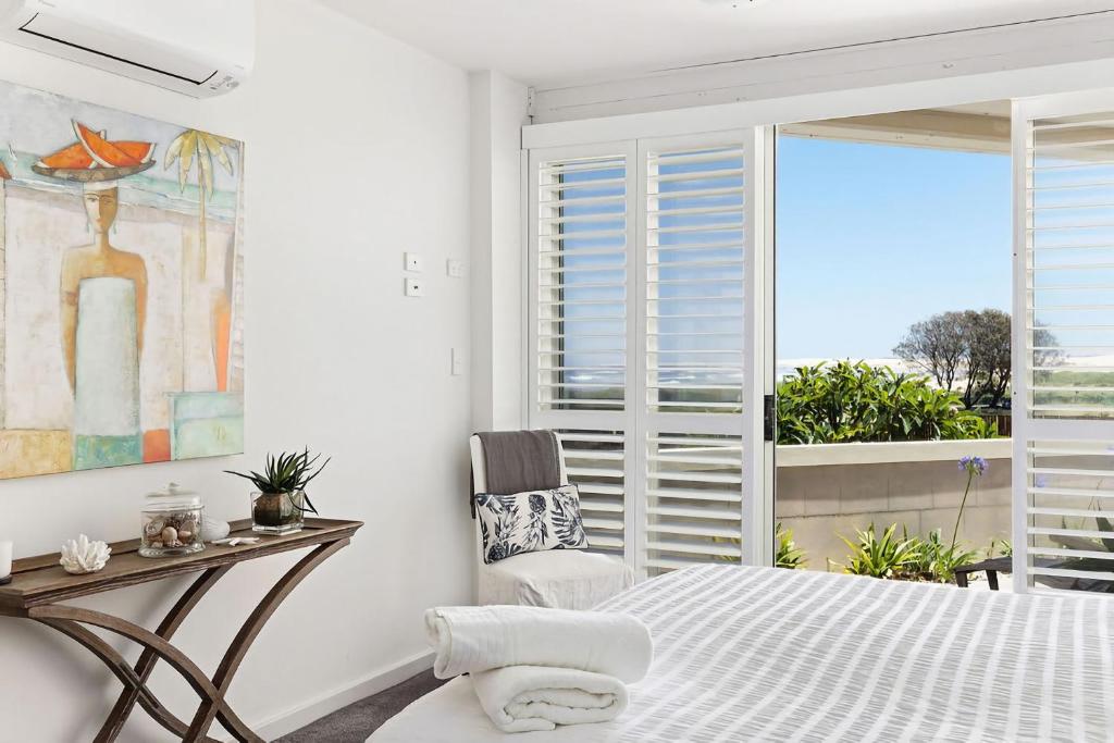 a bedroom with a bed and a table and a window at Birubi Beach Waterfront in Anna Bay