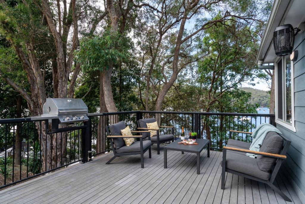 a deck with a grill and chairs and a table at Coal and Candle by Beach Stays in Berowra
