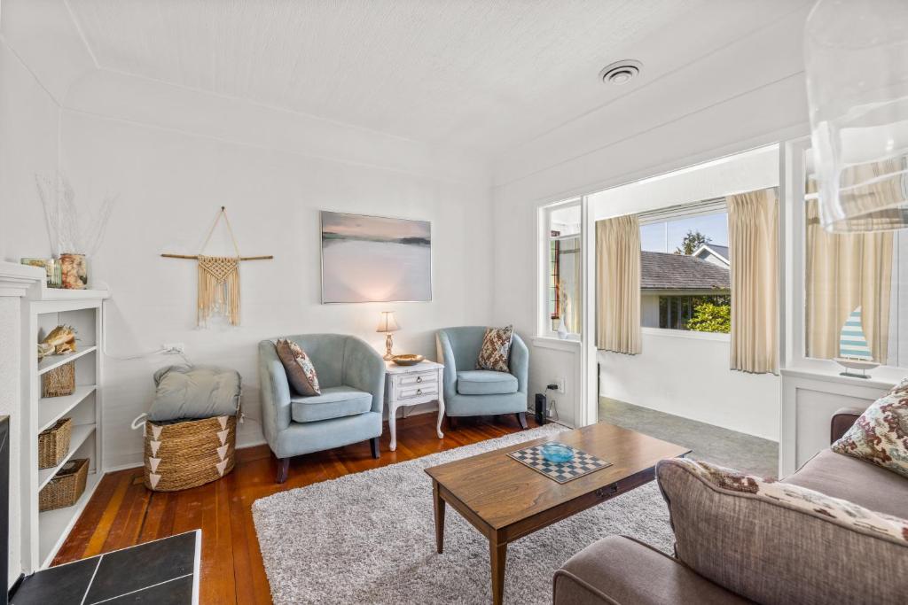 ein Wohnzimmer mit einem Sofa, Stühlen und einem Tisch in der Unterkunft Coastal Chic Retreat by Iris Properties! in Victoria