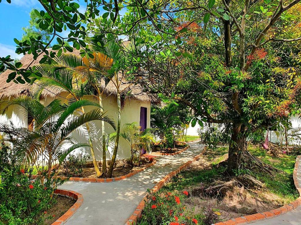 a path leading to a house with trees and flowers at Bohemiaz Resort and Spa Kampot in Kampot